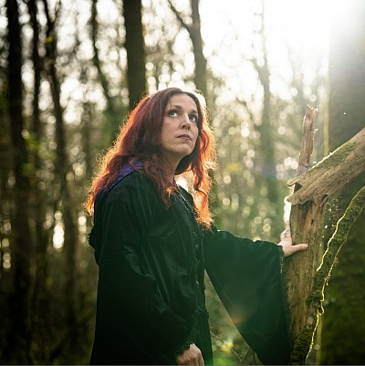 Elsy Eala, autrice, dans une forêt mystérieuse, évoquant l’univers de ses romans avec vampires et sorciers.